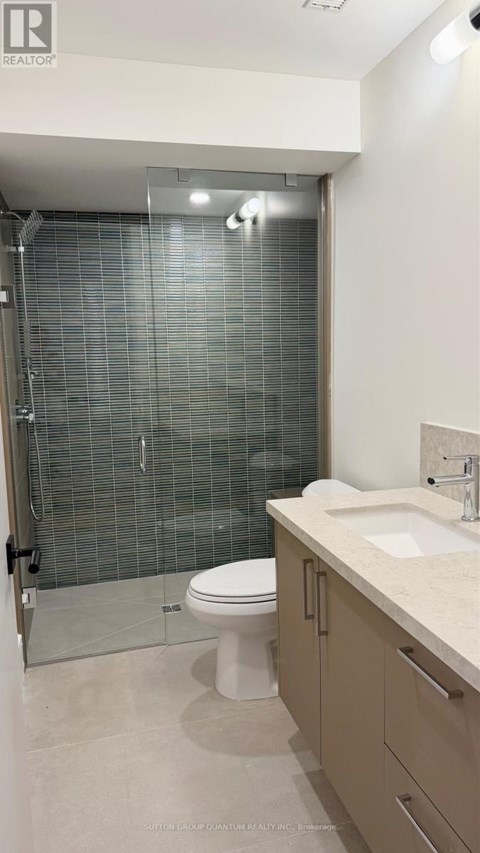 A white toilet is in a bathroom with a walk-in shower.