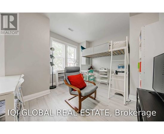 A room with a bunk bed and a chair with a red cushion.