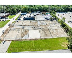 An aerial view of a construction site with a large open area and a few buildings in the background.