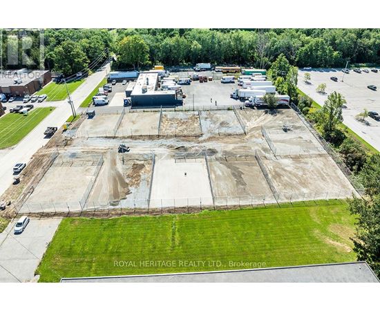 An aerial view of a construction site with a large open area and a few buildings in the background.