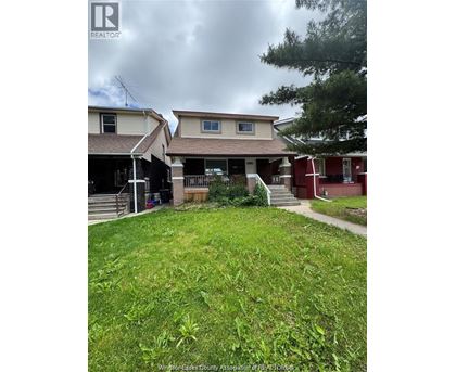 A grassy yard in front of a house with a sign that says REALTOR.
