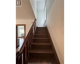 A staircase with a wooden handrail and steps leading to a doorway.