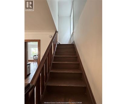 A staircase with a wooden handrail and steps leading to a doorway.