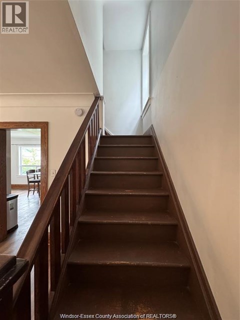 A staircase with a wooden handrail and steps leading to a doorway.