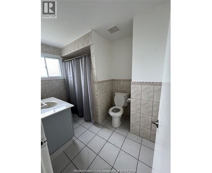 A bathroom with a toilet, sink, and shower curtain.