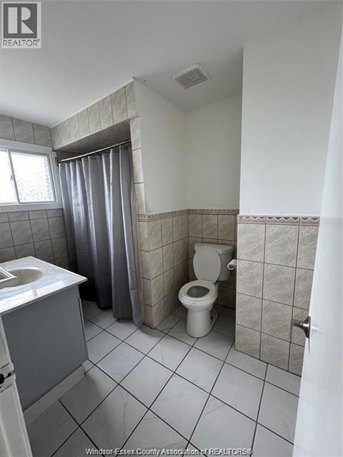 A bathroom with a toilet, sink, and shower curtain.