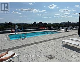 A person is sunbathing on a chair by a pool on a rooftop.