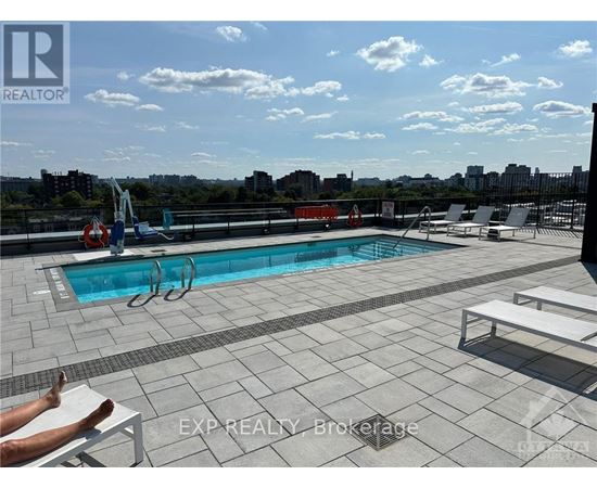 A person is sunbathing on a chair by a pool on a rooftop.