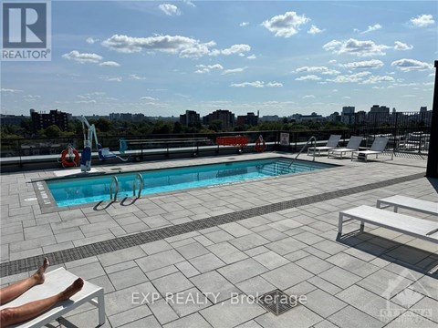 A person is sunbathing on a chair by a pool on a rooftop.