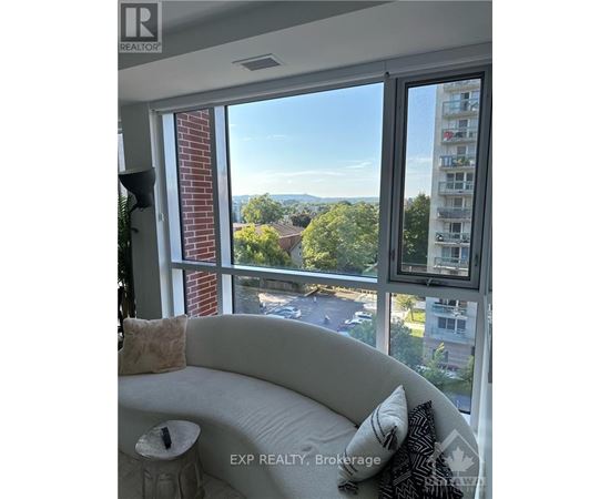 A living room with a couch and a window overlooking a street.