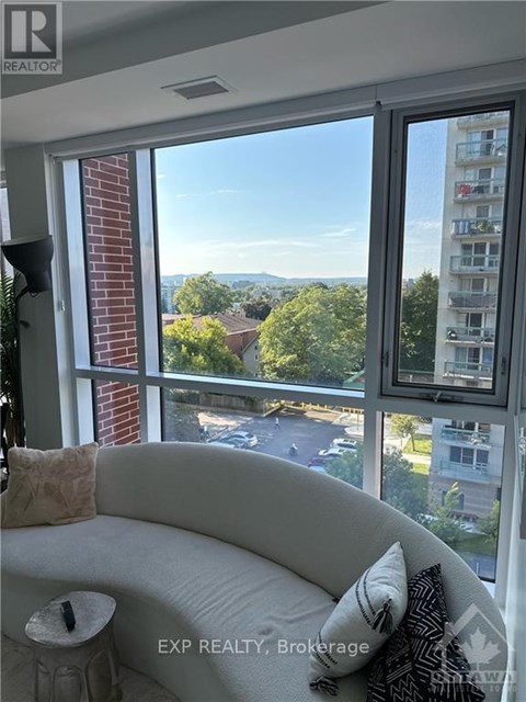 A living room with a couch and a window overlooking a street.