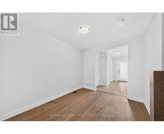 A spacious room with wooden flooring and white walls.