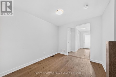 A spacious room with wooden flooring and white walls.