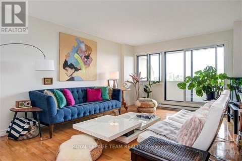A living room with a blue couch and a painting of a woman on the wall.