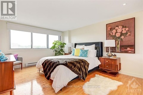 A bedroom with a large bed and a painting on the wall.