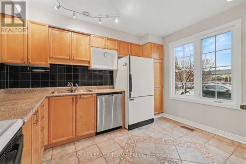 A kitchen with wooden cabinets and a black tile backsplash.