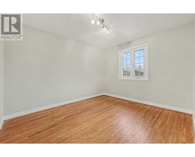 A room with wooden flooring and a window showing a view of trees.