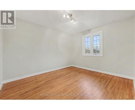 A room with wooden flooring and a window showing a view of trees.