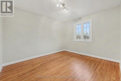 A room with wooden flooring and a window showing a view of trees.