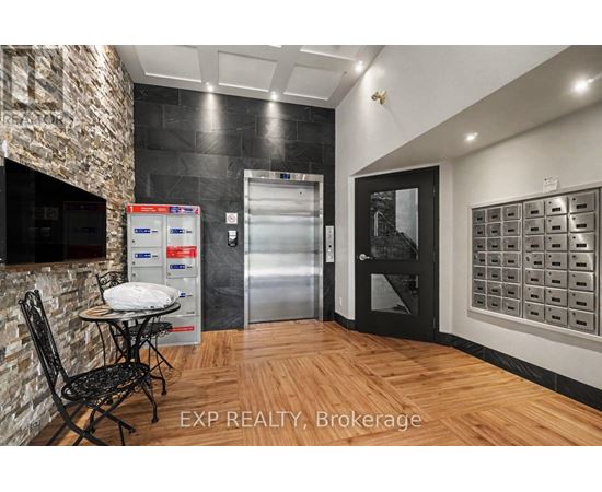 A kitchen area with a table and chairs, a fridge, and a wall of mailboxes.