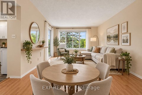 A well-lit, spacious living room with a dining table and chairs, and a couch with pillows.