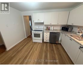 A kitchen with white cabinets and a wooden floor.