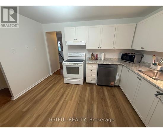 A kitchen with white cabinets and a wooden floor.