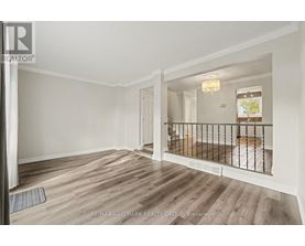 A spacious room with wooden flooring and a balcony with a railing.