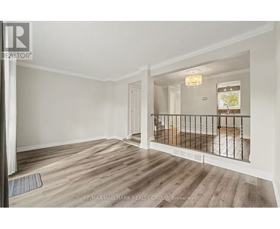A spacious room with wooden flooring and a balcony with a railing.