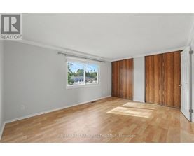 A room with wooden flooring and a window showing a view of trees.