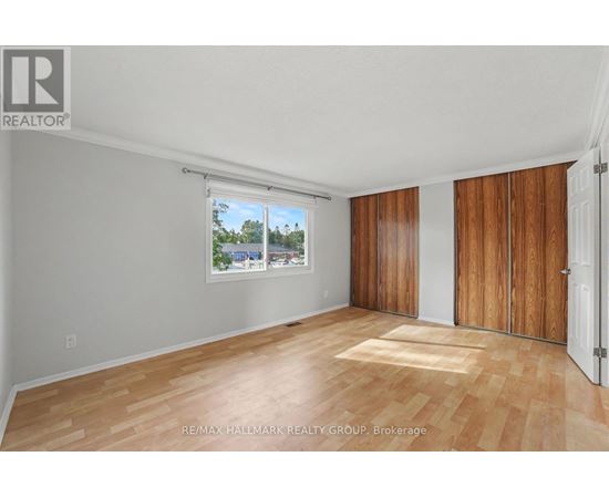 A room with wooden flooring and a window showing a view of trees.