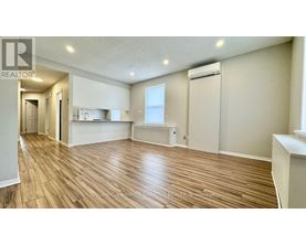 A spacious room with wooden flooring and a window.