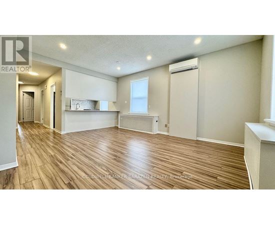 A spacious room with wooden flooring and a window.