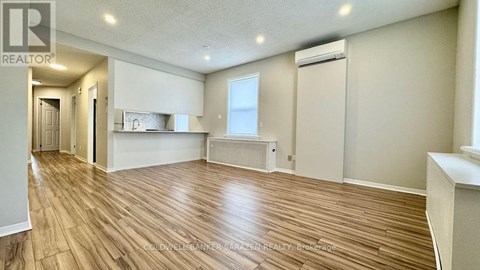 A spacious room with wooden flooring and a window.