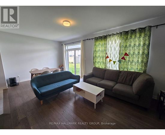A living room with a blue couch, a white coffee table, and a window with curtains.