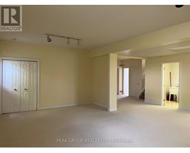 A spacious room with a door on the left and a hallway leading to another room on the right.
