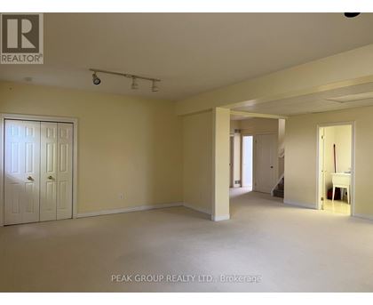 A spacious room with a door on the left and a hallway leading to another room on the right.