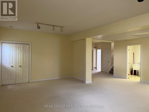 A spacious room with a door on the left and a hallway leading to another room on the right.