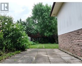 A backyard with a concrete walkway and a brick wall.