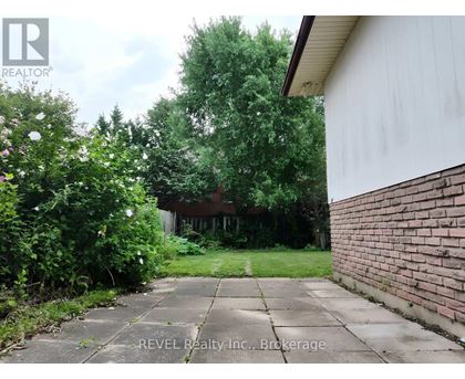 A backyard with a concrete walkway and a brick wall.