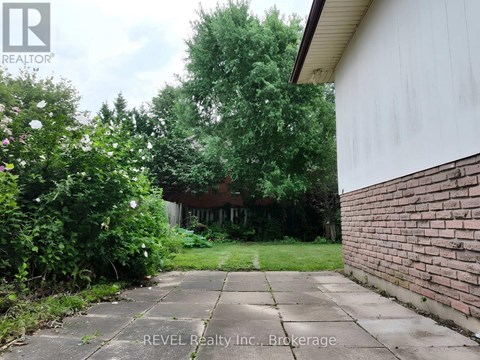 A backyard with a concrete walkway and a brick wall.
