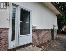 A white door with a glass window is on a white house with a brick wall.