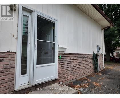 A white door with a glass window is on a white house with a brick wall.