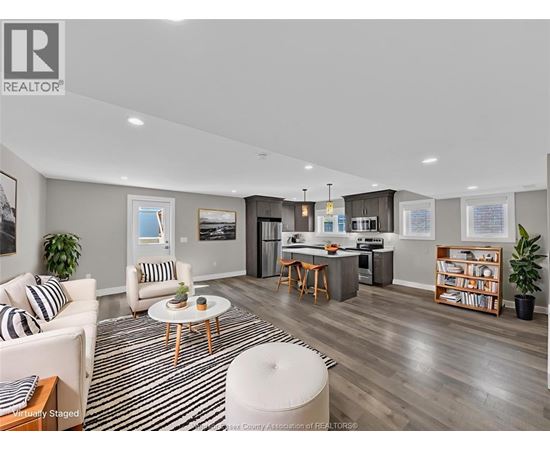 A modern living room with a striped rug and a kitchen area in the background.