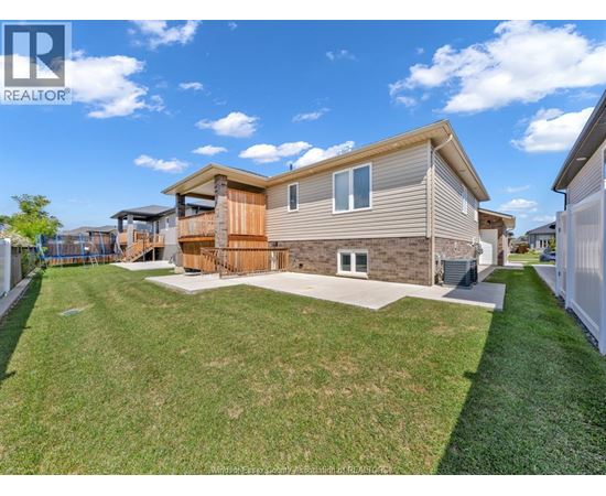 A realtor photo of a house with a brown and beige exterior, a white garage door, and a green lawn.