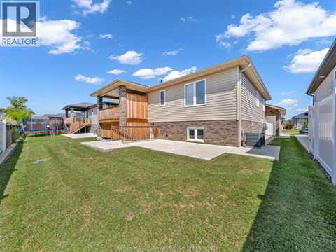 A realtor photo of a house with a brown and beige exterior, a white garage door, and a green lawn.