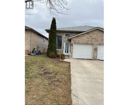 A house with a driveway and a tree in front.