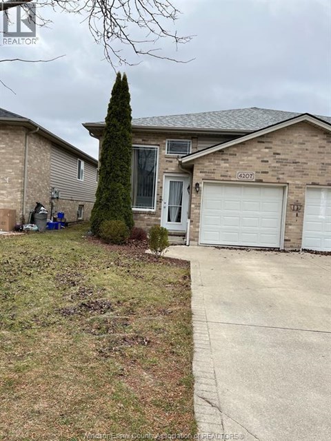 A house with a driveway and a tree in front.