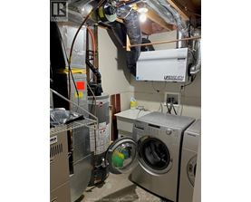 A man is working on a washing machine in a laundry room.