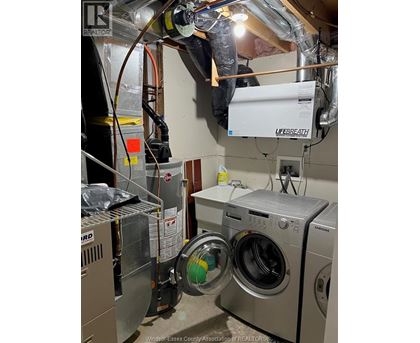 A man is working on a washing machine in a laundry room.